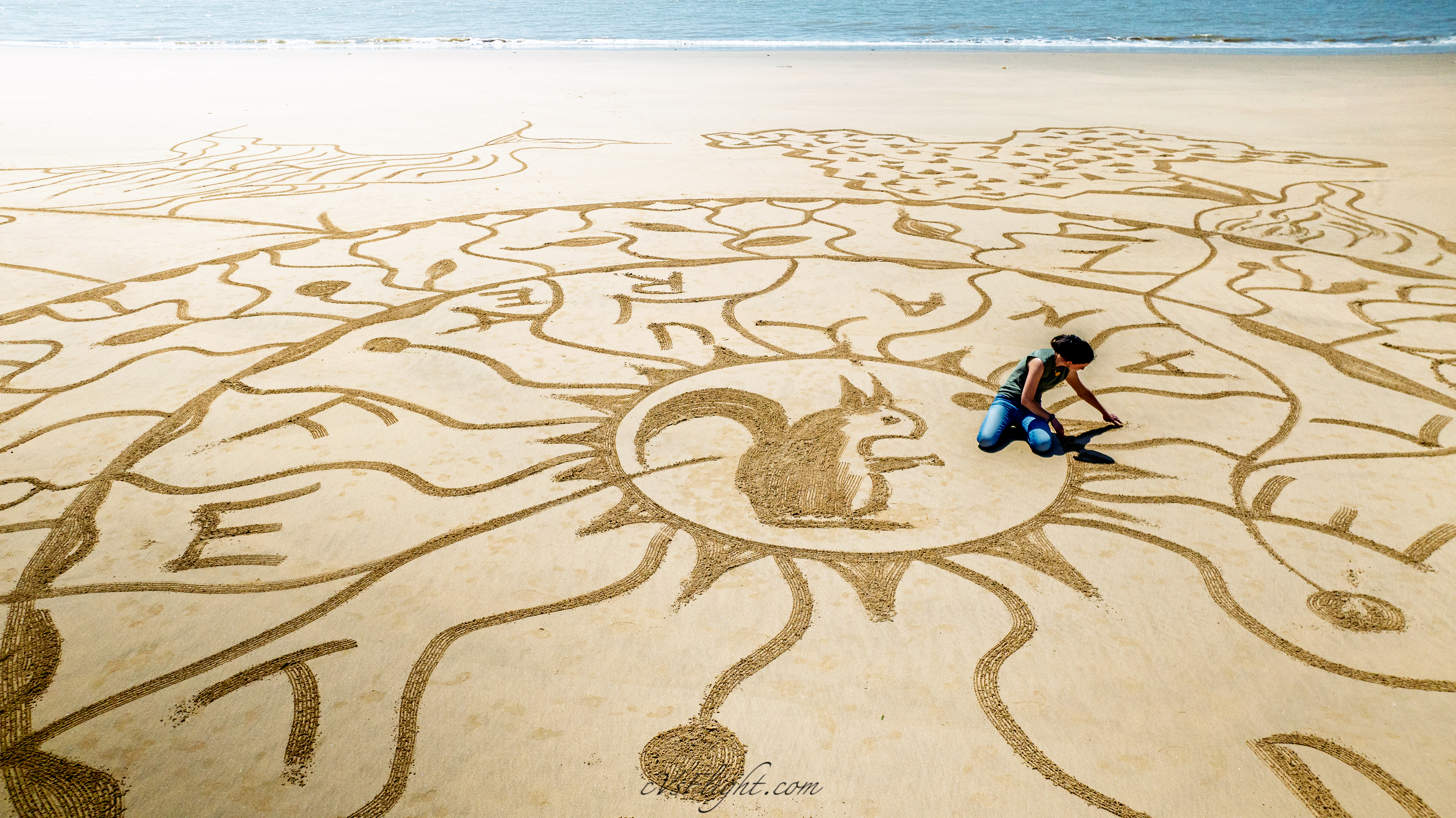 L’artiste assise au milieu de son dessin sur le sable